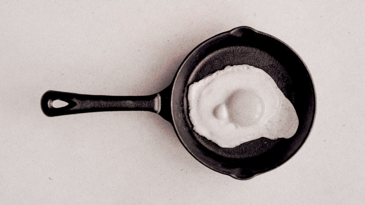Photograph of an egg frying in a pan, edited to resemble the 1987 'this is your brain on drugs' PSA.