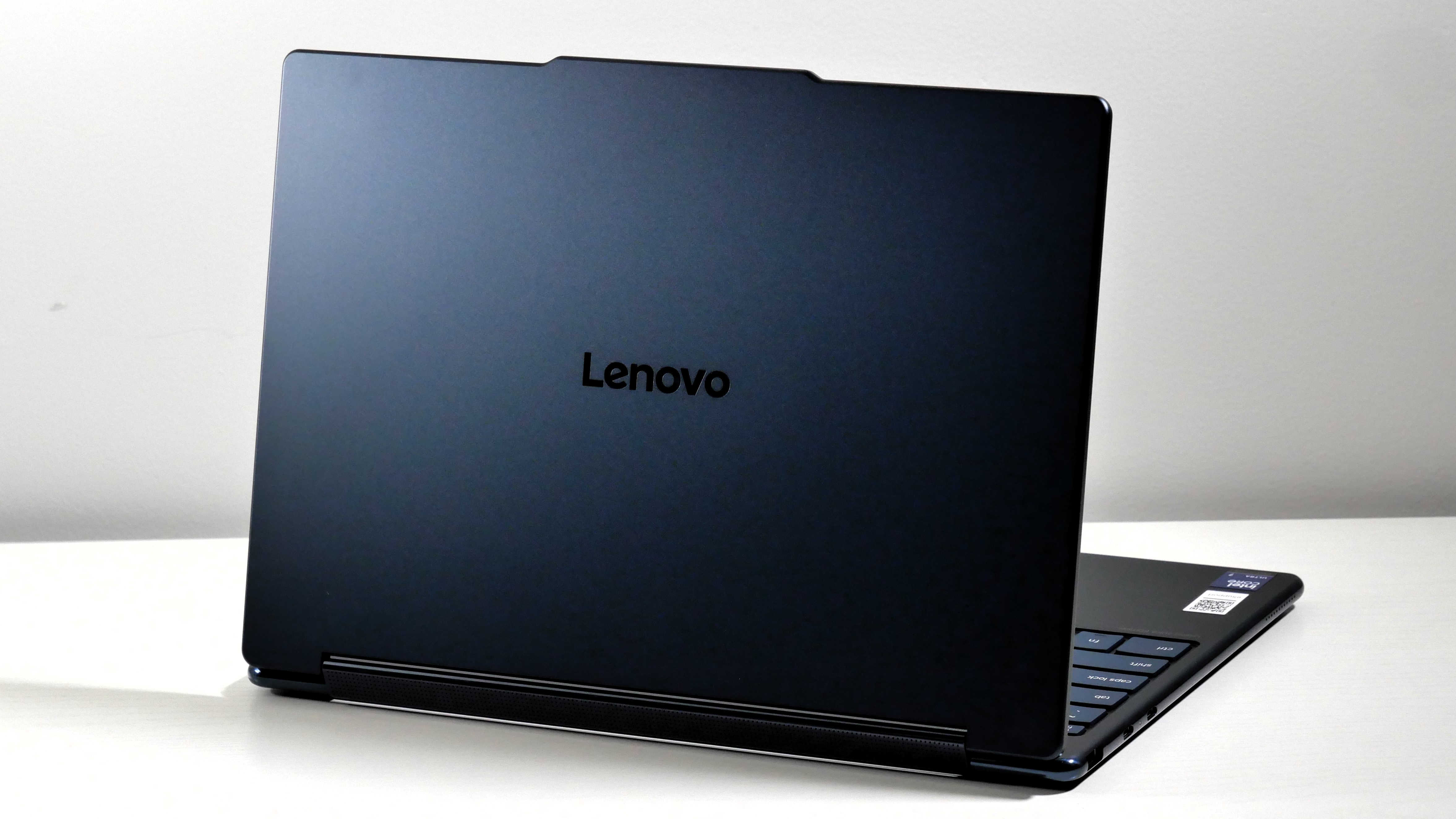 Lenovo Yoga 9i 2-in-1 Aura Edition open on a white desk, highlighting the cosmic blue lid.