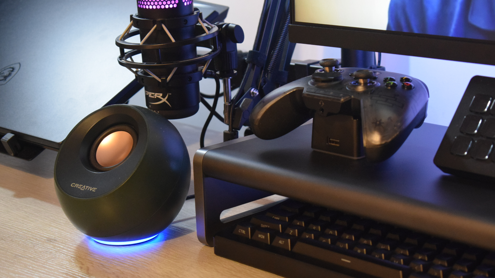 Photo of the Anker 675 USB-C Docking Station as part of a setup showing Creative Pebble speakers, an MSI gaming laptop, a BIGBIG WON Rainbow wireless gamepad on its charging dock, a hyperX microphone, a Stream Deck, a wireless keyboard, and an MSI monitor.