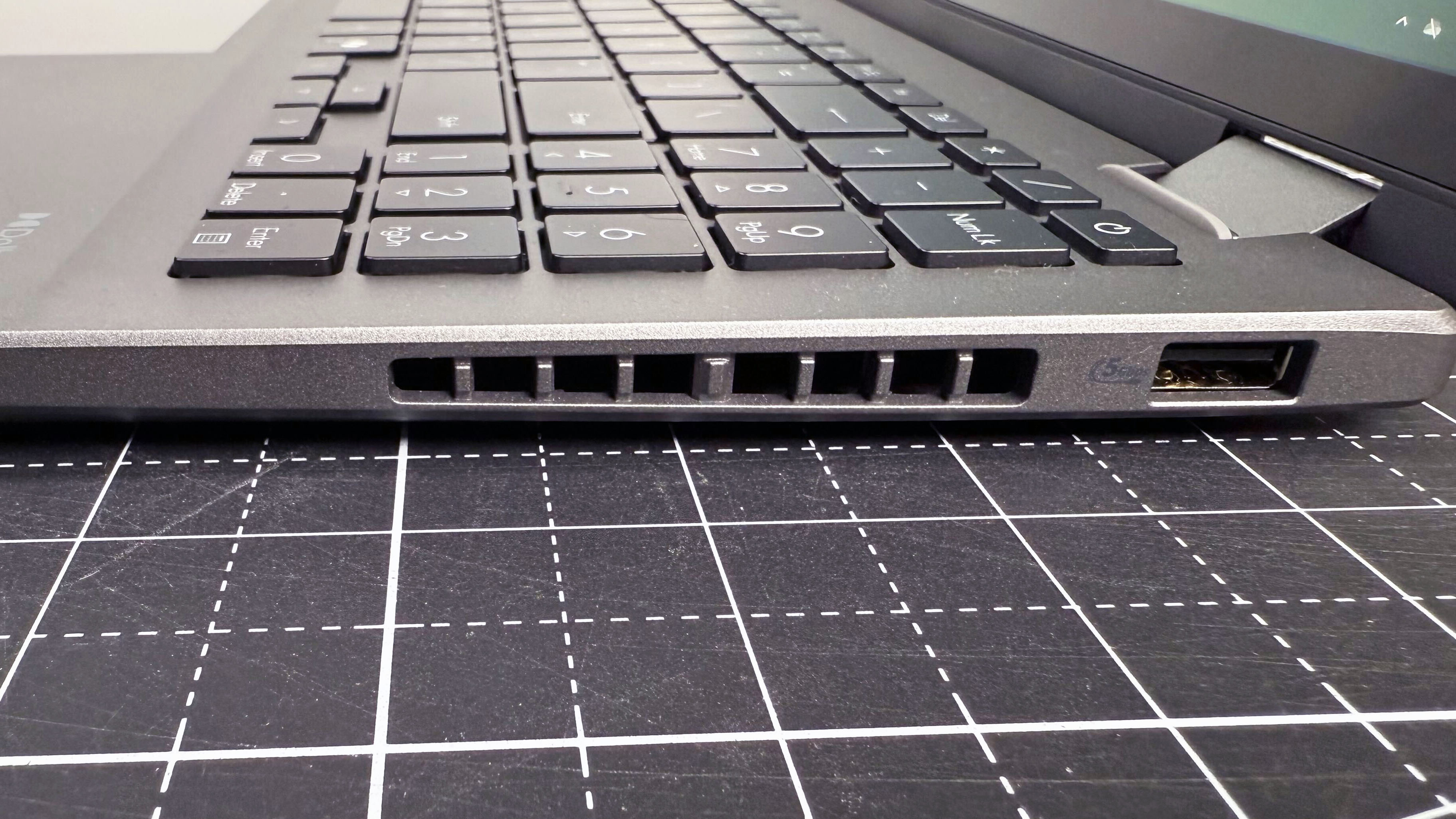 A close-up of the left-hand ports on the Asus Vivobook 16 Flip convertible laptop, against a black and white desk.