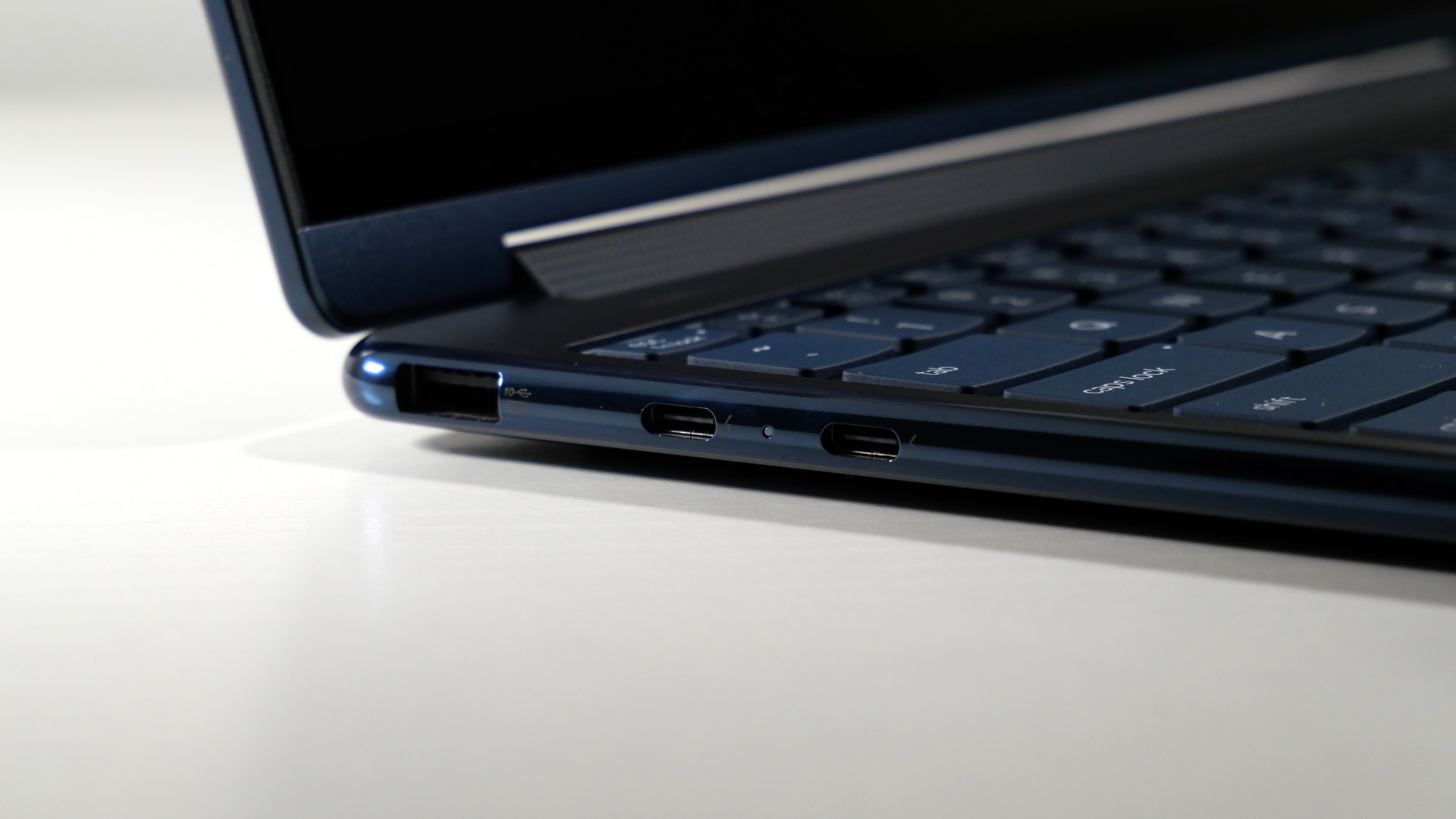 Lenovo Yoga 9i 2-in-1 Aura Edition open on a white desk, highlighting the ports on the left, including one USB Type-A and two USB Type-C.