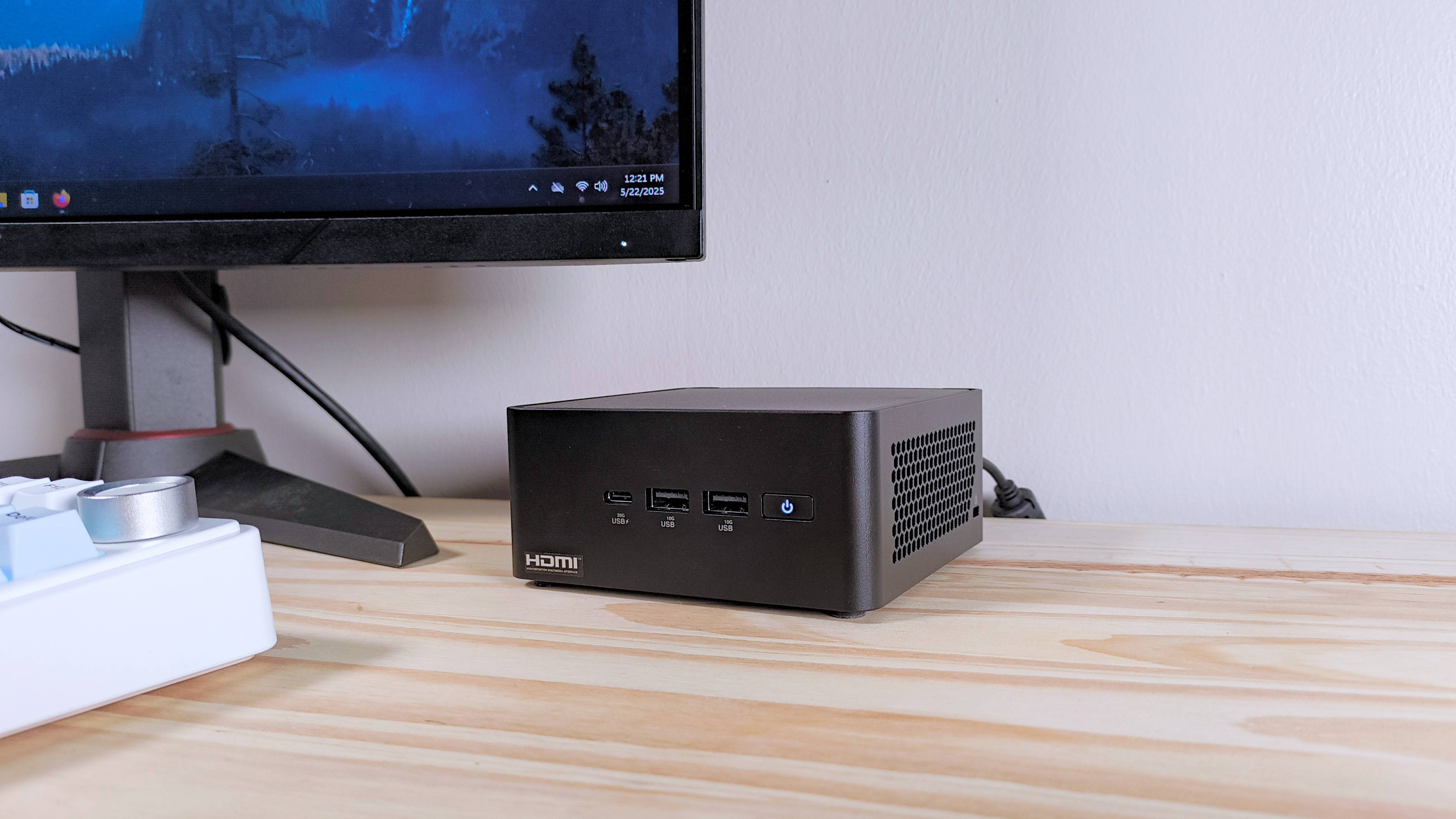 Close up of the Asus NUC 14 Pro mini PC on a table next to a monitor and keyboard