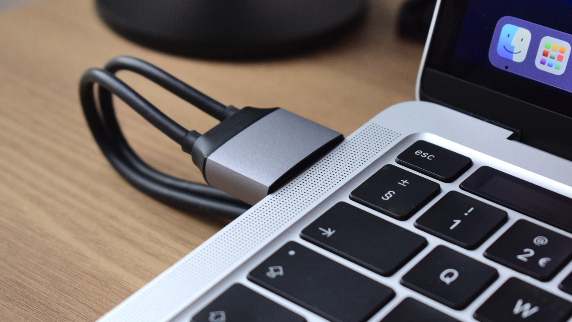 A close-up image showing a MacBook Air on top of the Satechi Dual Dock Stand connecting to its two left-facing Thunderbolt ports.