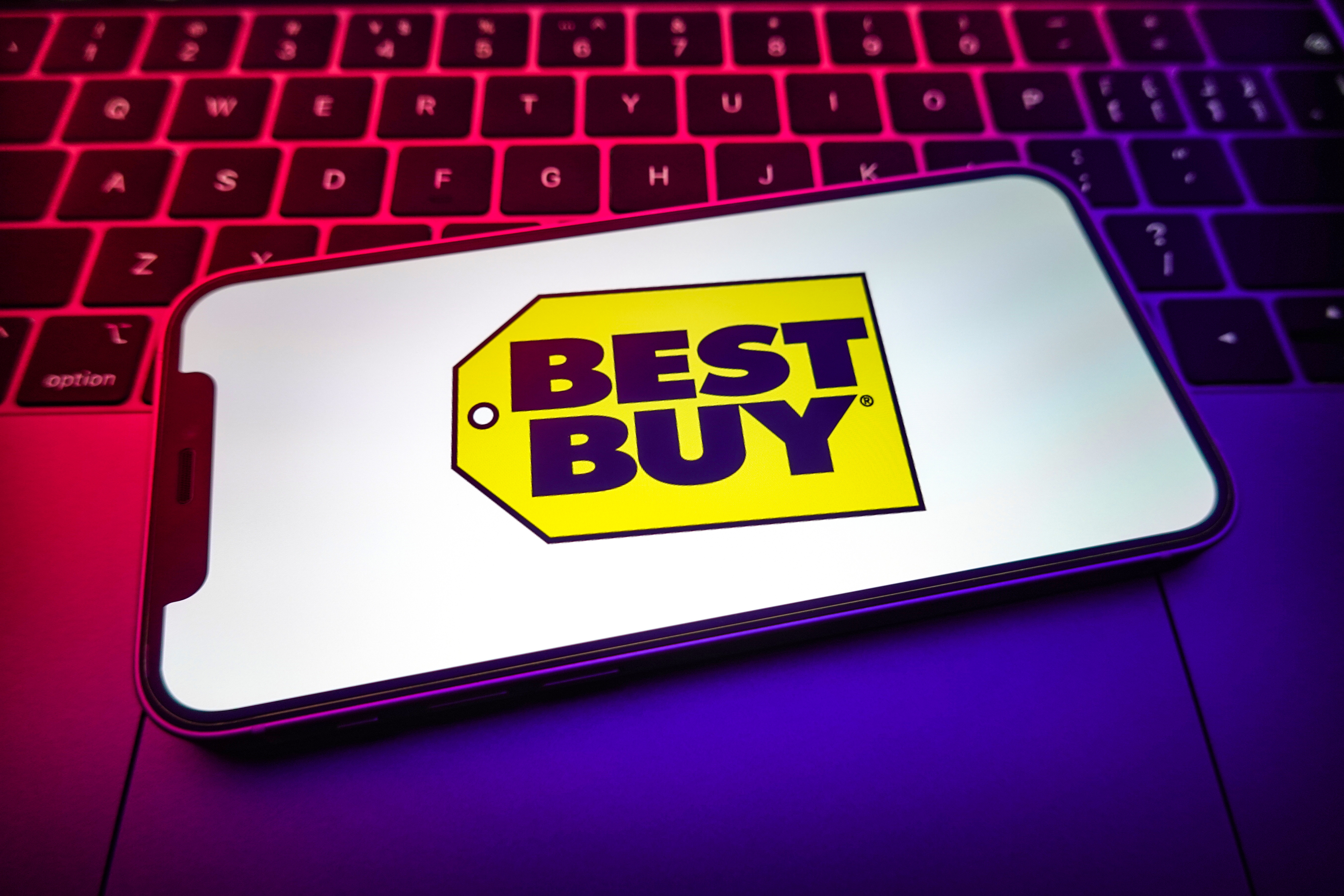 Smartphone with Best Buy logo on screen laying on a laptop
