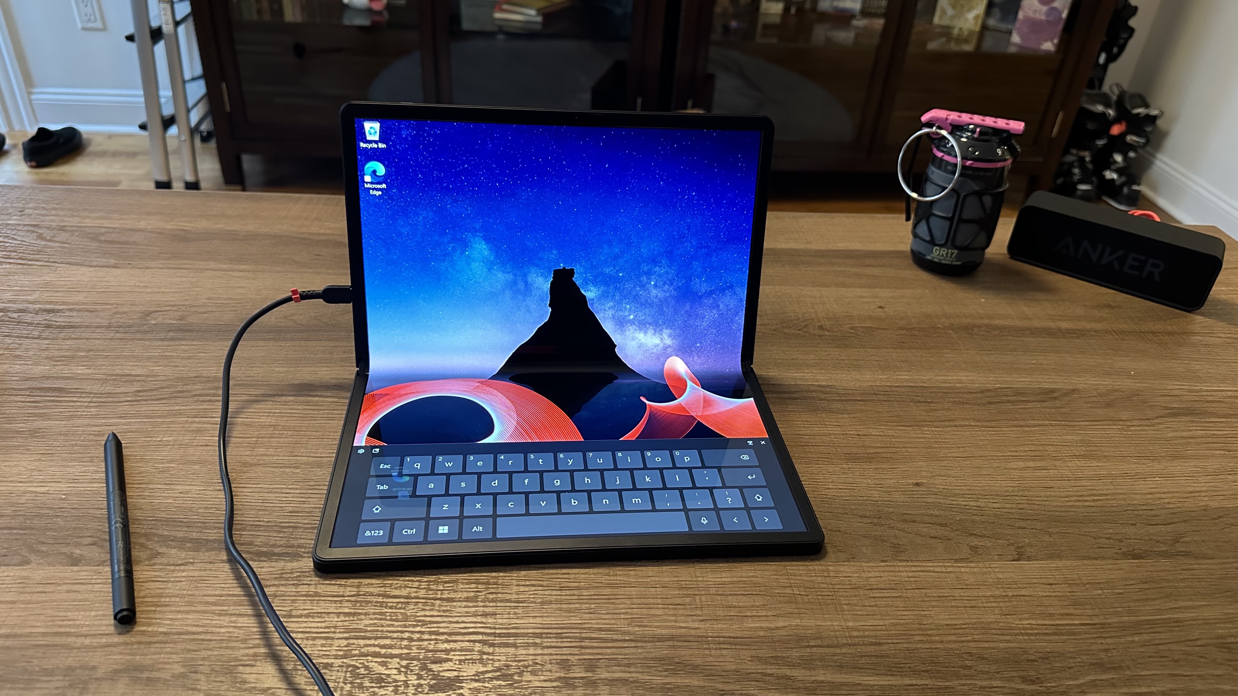 Lenovo ThinkPad X1 Fold 16 Gen 1 folded on a desk with a digital keyboard visible.