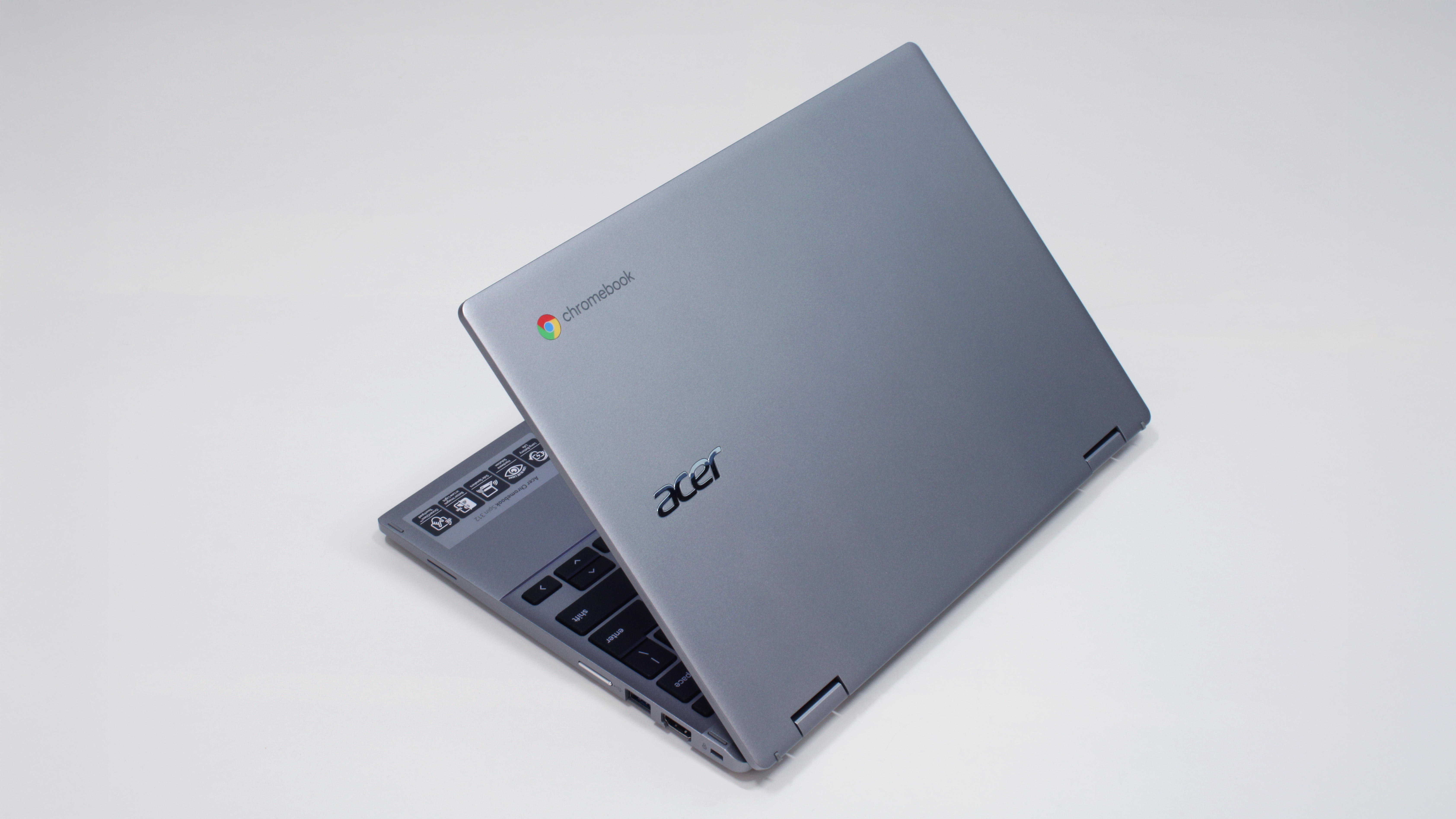 A silver laptop against a white background, its lid halfway open with the brand logo facing the camera.