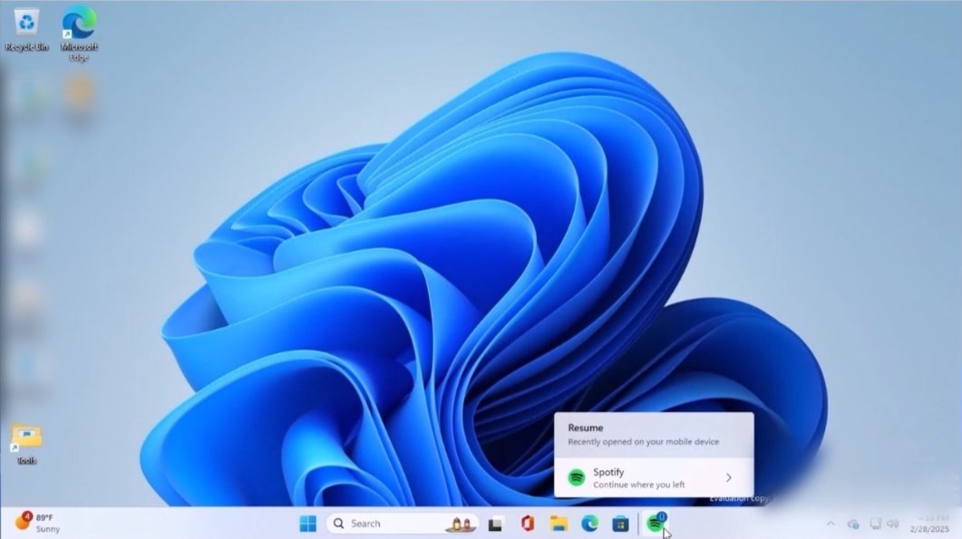 Windows desktop showing Spotify icon in the taskbar with a badge and message highlighting the Cross Device Resume feature