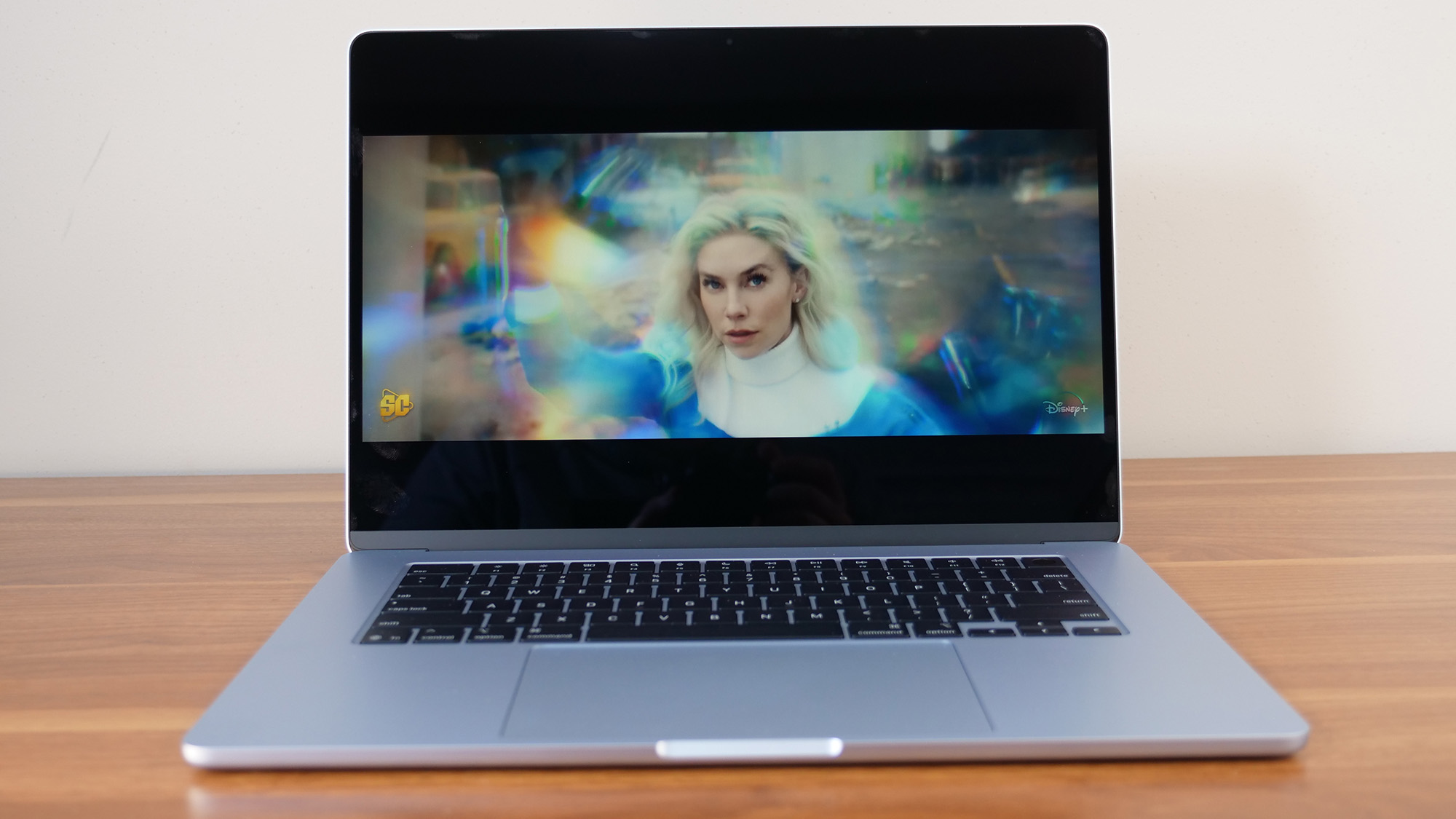Apple MacBook Air 15-inch M4 on a wooden table with a movie trailer playing on the screen.