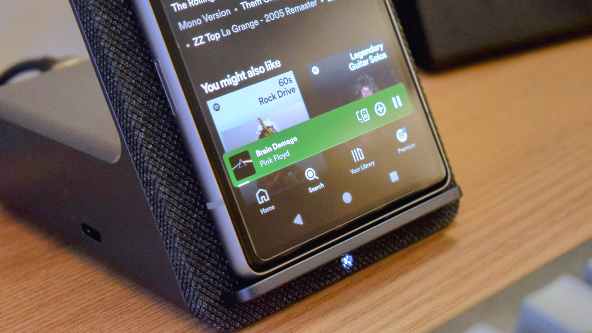 A close-up photo of the Dell Dual Charge Dock with QI wireless charging docking station showing the wireless charging indicator light lit up as it charges a Google Pixel 7a smartphone.